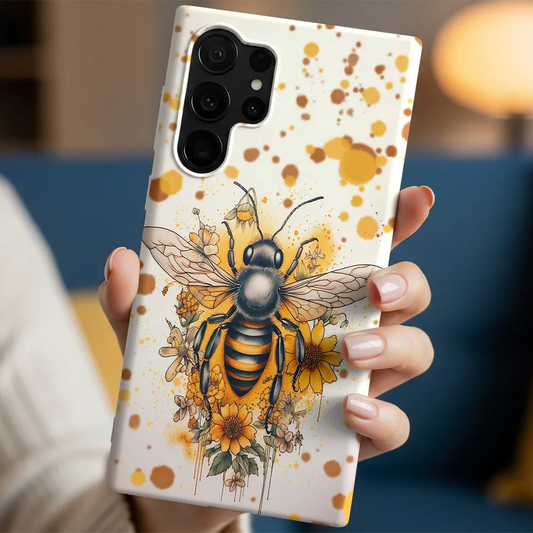 In-hand lifestyle shot holding the Golden Garden Bee case with warm amber tones and glossy finish.